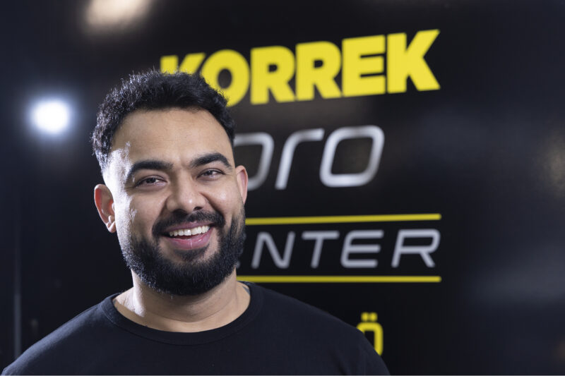 KPC P-Töölön yrittäjä Rafi hymyilee KPC-logon edessä